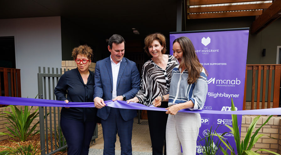 4 people cutting a purple ribbon to open a house