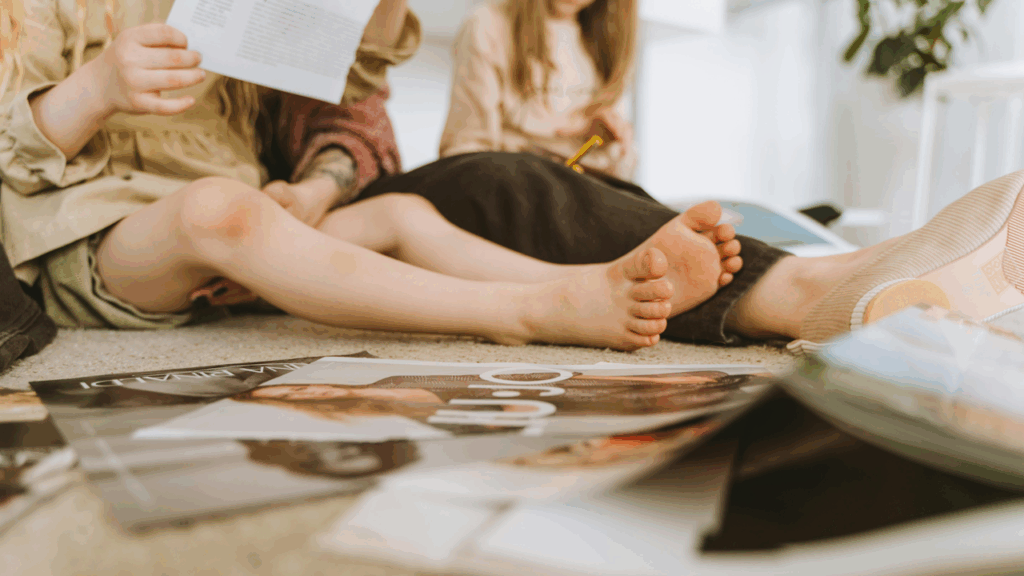 Two children and an adult looking through magazines on the floor