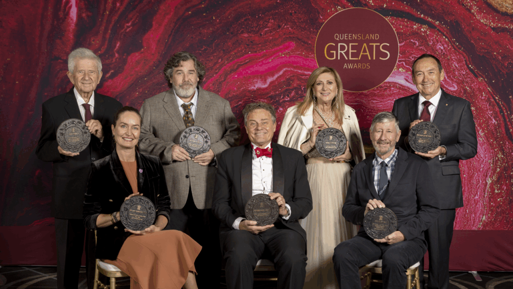 Queensland Great Awards Winners sitting and standing with their awards