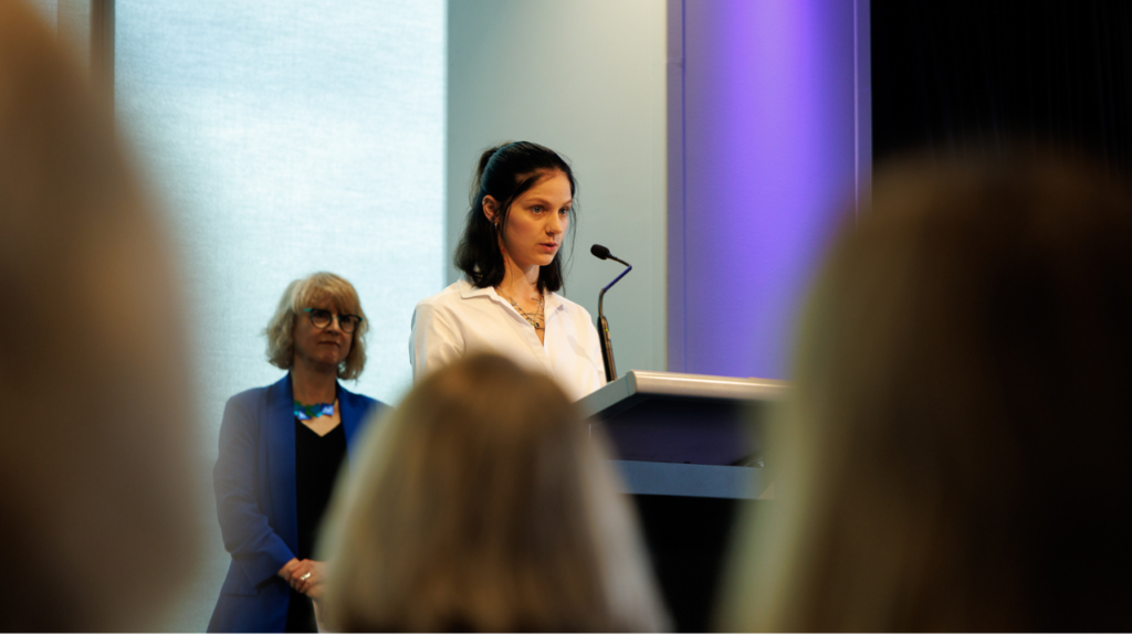 Micky speaking at a lectern at the Annual Forum